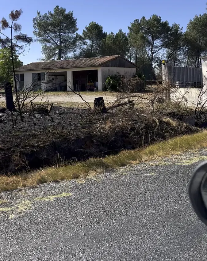 Après le passage du feu : le sol brûlé s'arrête au bord du terrain dégagé, la grange reste intacte